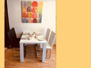 a white table with chairs and a painting on the wall at Gaestehaus _ Sandra Objekt _ 90541 in Bützow