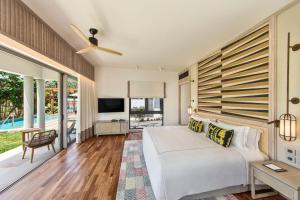 a bedroom with a large white bed and a large window at Anantara Iko Mauritius Resort & Villas in Blue Bay