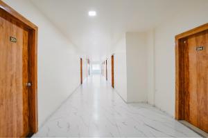 an empty hallway with white walls and wooden doors at Via Chaitanya Inn in Pune +25 photos