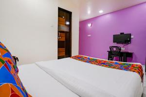 a bedroom with a white bed with a purple wall at Via Chaitanya Inn in Pune