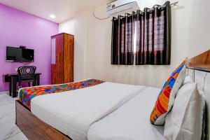 a bedroom with a white bed and a tv at Via Chaitanya Inn in Pune