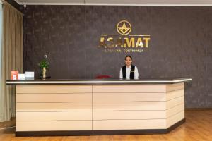 a woman standing at a counter in front of a wall at Azamat Hotel in Astana