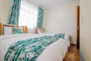 a bedroom with two beds and a window with curtains at Tropical themed 3BR and DSQ Apartment in Nairobi