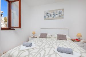 a white bedroom with a large bed with two towels at Rooms Ivo in Dubrovnik