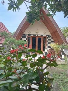 a small house with a triangular roof with red flowers at Meno Smile Cottages in Gili Meno