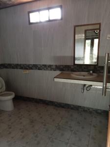 a bathroom with a sink and a toilet and a mirror at Meno Smile Cottages in Gili Meno