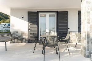 un patio con tavolo in vetro e sedie di Appartamento Emma con Piscina - Vista Mare"Tenuta Croce" a Salerno