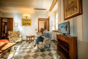 a woman sitting in a chair in a living room with a laptop at Park Hotel Regina - with air-condition and pool in Bagni di Lucca