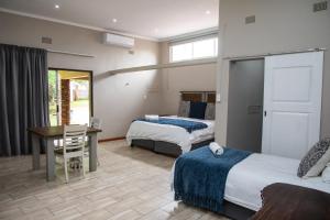 een slaapkamer met 2 bedden, een bureau en een tafel bij Opstal Guestfarm in Potchefstroom