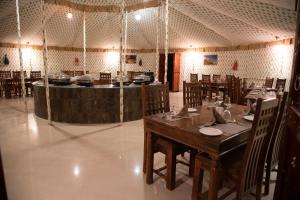 ein Restaurant mit einem Tisch, Stühlen und einer Theke in der Unterkunft Atithi Camp & Resort in Pushkar