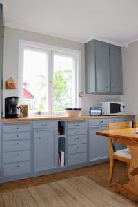 cocina con armarios azules, mesa y ventana en Familjevänligt hus med stor trädgård en Vallsta