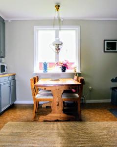 a kitchen with a wooden table and a window at Familjevänligt hus med stor trädgård in Vallsta