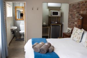 1 dormitorio con cama blanca y baño en Opstal Guestfarm, en Potchefstroom