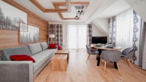 a living room with a couch and a table at Apartamenty Sun & Snow Resorts G Białka Tatrzańska z sauną in Białka Tatrzańska
