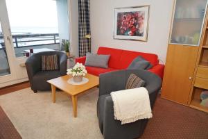 a living room with a red couch and two chairs at Ferienwohnung zur Hafenseite _ 200 in Damp