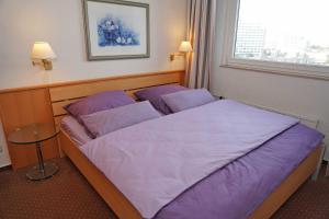 a bedroom with two beds with purple sheets and a window at Ferienwohnung zur Hafenseite _ 200 in Damp