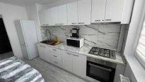 a kitchen with white cabinets and a stove and a microwave at APARTAMENT 2 CAMERE CENTRU ONESTI in Onești
