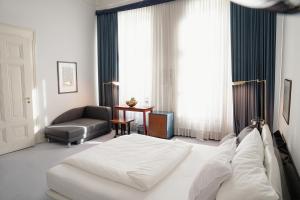 - une chambre avec un lit blanc et un canapé dans l'établissement Domicil Hotel Bonn, à Bonn