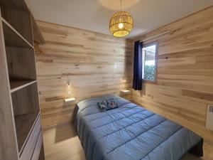 - une chambre avec un lit bleu dans un mur en bois dans l'établissement VILLAGE DE GITES LA TRUFFIERE, à Orliaguet