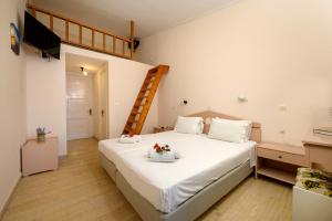 Un dormitorio con una cama con sábanas blancas y una escalera en Siora Leni Hotel en Benitses