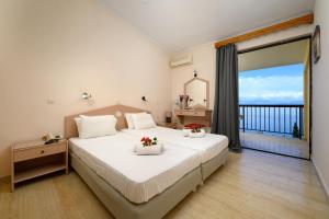 a bedroom with a large bed and a large window at Siora Leni Hotel in Benitses