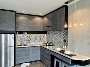 a kitchen with gray cabinets and a stainless steel refrigerator at Kamala Beach P72 Exclusive Junior Suite in Bang Tao Beach