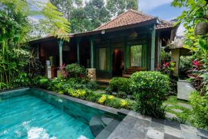 a villa with a swimming pool in front of a house at Bunut Garden Luxury Private Villa in Ubud