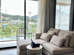a living room with a couch and a large window at Kamala Beach P72 Exclusive Junior Suite in Bang Tao Beach
