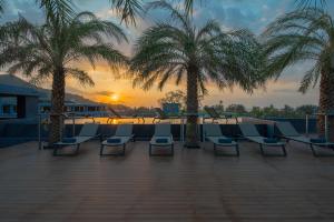 a group of chairs and palm trees on a patio at Kamala Beach P72 Exclusive Junior Suite in Bang Tao Beach