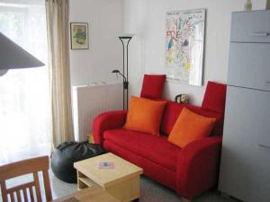 ein rotes Sofa mit orangefarbenen Kissen im Wohnzimmer in der Unterkunft Zinnowitz Haus Isabella Wohnung 8 W8IZ in Zinnowitz
