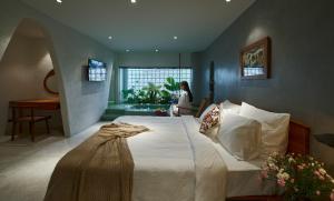 a bedroom with a large bed and a woman sitting in a chair at Barbados Cherry Villa in Hoi An