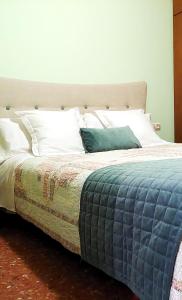 ein großes Bett mit blauem Kissen darauf in der Unterkunft Vivienda Turística el Ciclamen in Mora de Rubielos