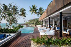 un complexe avec une piscine, des chaises et l'océan dans l'établissement Ahu Bay, à Ahungalla