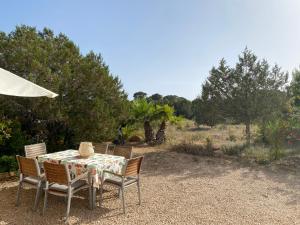 a table and chairs with an umbrella and trees at Ses Oliveres in Cala Saona