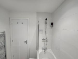 uma casa de banho branca com um chuveiro e uma banheira em New build home with WI-FI, Smart TV, dedicated office floor, large terrace and Free parking em Milton Keynes