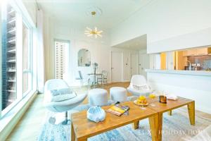 a living room with a table and white chairs at LUX Marina Promenade Penthouse Suite in Dubai