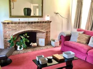 a living room with a pink couch and a fireplace at Cosy Farmhouse Escape in Monmouthshire in Wolves Newton
