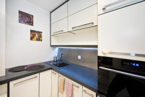 a kitchen with white cabinets and a sink at YOURAPART Gdansk Morena in Gdańsk