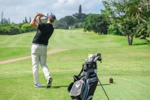 een man zwaaiend met een golfclub op een golfbaan bij San Lameer Villa 3303 - 2 Bedroom Classic - 4 pax - San Lameer Rental Agency in Southbroom