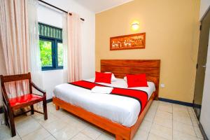 a bedroom with a bed with red pillows and a chair at Water Front Hotel Kandy in Kandy