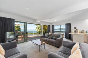 a living room with a couch and a tv and a table at Lakeside Terrace - Taupo Holiday Home in Taupo