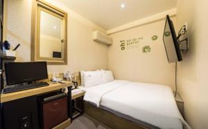 Habitación pequeña con cama y escritorio con ordenador. en Hotel Daisy en Seúl