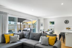 uma sala de estar com um sofá cinzento com almofadas amarelas em Contemporary Comfort - Masterton Holiday Home em Masterton