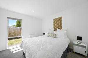 a white bedroom with a large bed and a window at Contemporary Comfort - Masterton Holiday Home in Masterton