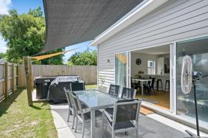 a backyard patio with a glass table and chairs at Contemporary Comfort - Masterton Holiday Home in Masterton