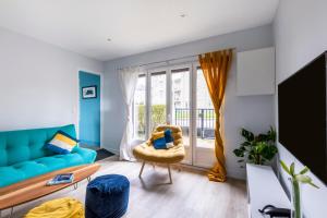 ein Wohnzimmer mit einem blauen Sofa und einem Stuhl in der Unterkunft Le Domaine des pins - Maison 2 Chambres vue mer in Le Tréport