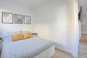 a white bedroom with a bed and three pictures on the wall at Le Vitry - Appt 2 Chambres à 20min Orly in Vitry-sur-Seine
