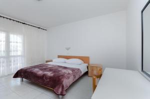 ein weißes Schlafzimmer mit einem Bett und einem Fenster in der Unterkunft Apartments Luce in Lopar