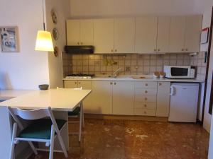 una cucina con mobili bianchi, un tavolo e un microonde di Casa Adriana a Rapallo