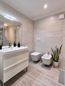 a white bathroom with a sink and a toilet at Life is Beautiful Design LOFT Navigli Romolo, SmartTV, WiFi, AC and street parking in Milan +13 photos